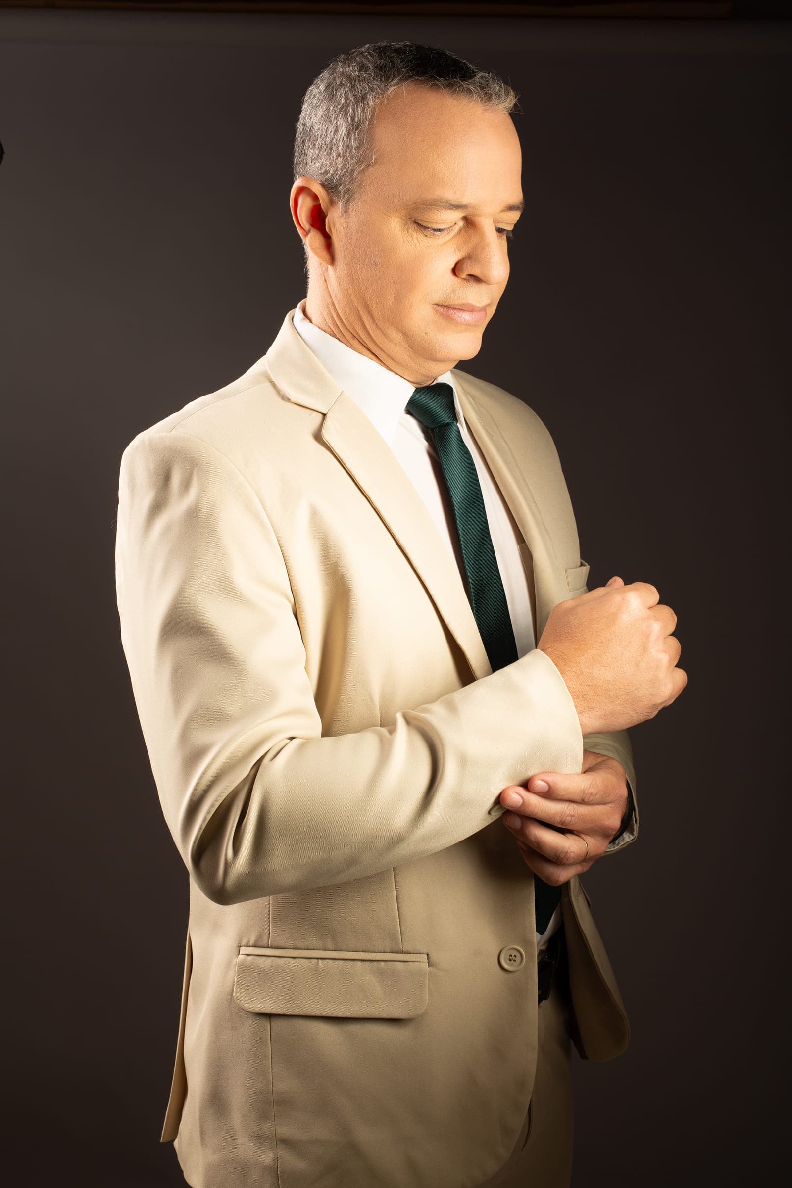 Paulo Crispim ajustando o punho da camisa, de terno claro e gravata
